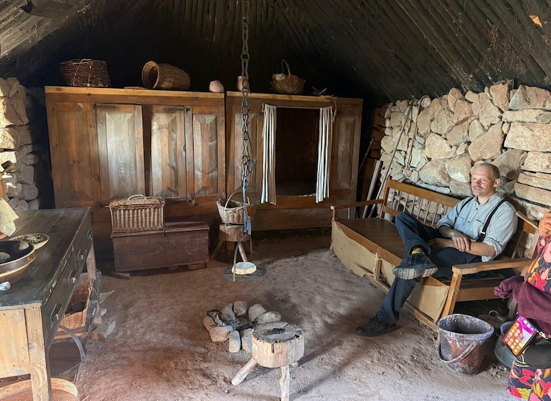 A rustic interior with wooden furniture, a stone wall, and a fire pit. 3