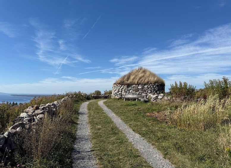 A stone wall with a grass-covered mound, a gravel path, and a clear blue sky. 2