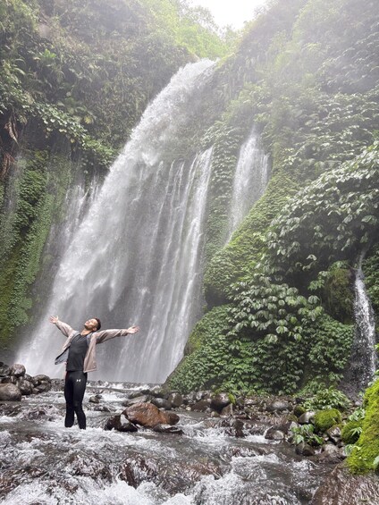 A waterfall with a person standing in front of it. 2