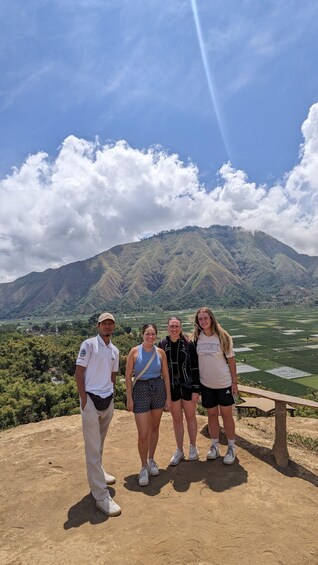 Four people standing on a hill with a mountainous landscape in the background. 4