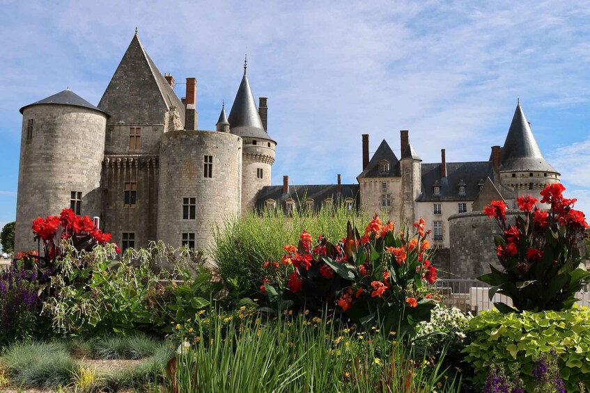 A historic castle with multiple towers and a well-maintained garden with vibrant flowers. 4