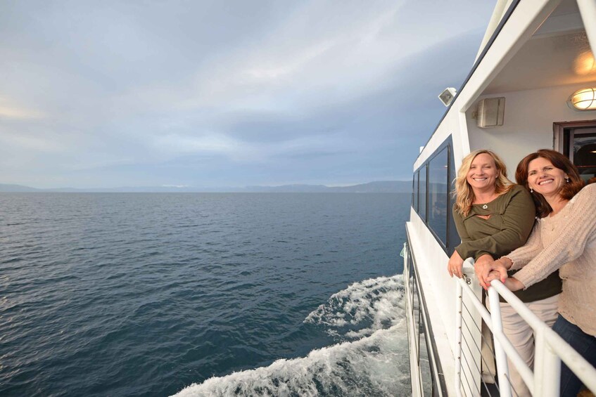 A boat with two people leaning on the railing, looking out at the ocean. 3