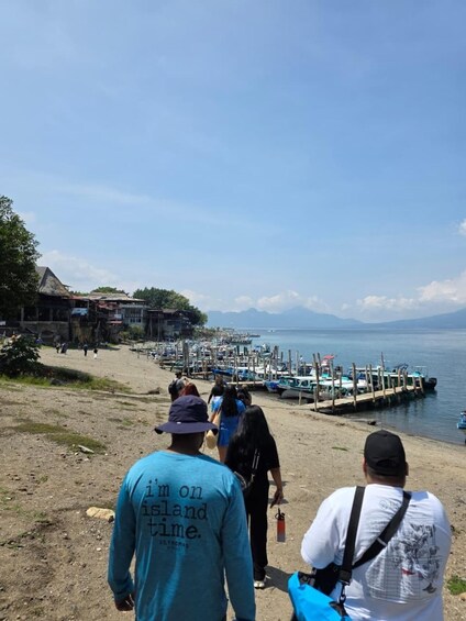 A beach with people walking, boats docked, and a clear sky. 4