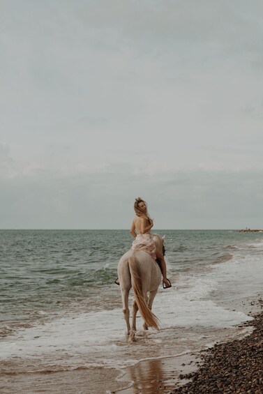 A person riding a horse along a beach with the sea in the background. 3