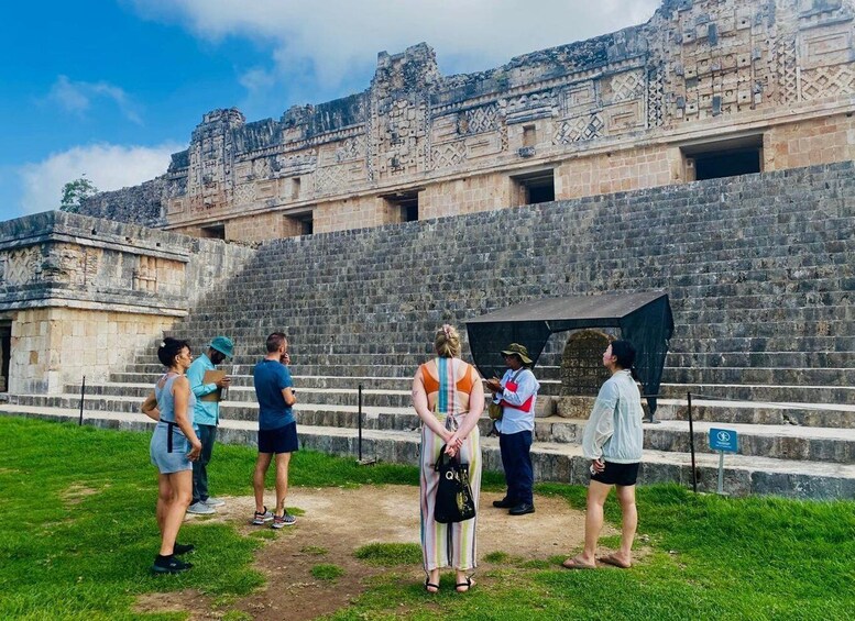 A group of tourists at an ancient Mayan ruin with stone steps and a large stone structure. 3