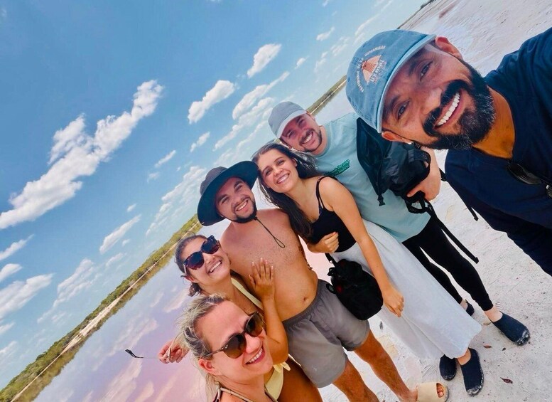A group of people on a beach with a clear sky and distant trees. 1