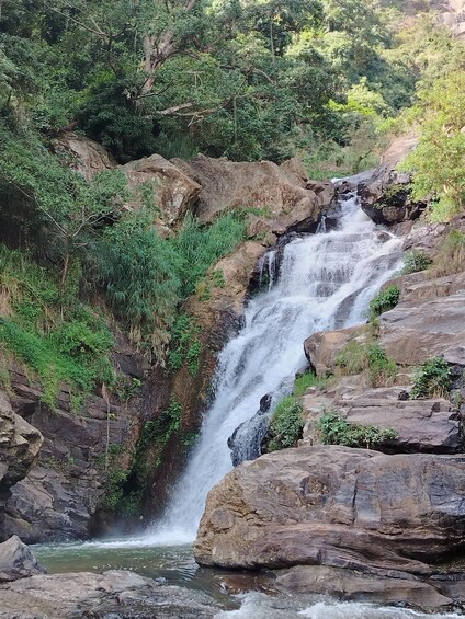 A multi-tiered waterfall surrounded by rocky terrain and dense greenery. 3
