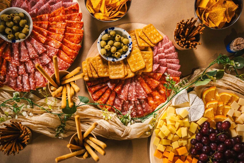 A charcuterie board with various meats, cheeses, olives, crackers, and fruits. 4