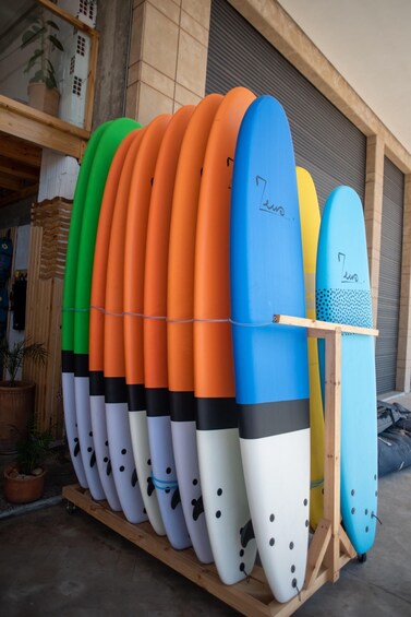 A row of surfboards on a wooden rack outside a building. 5