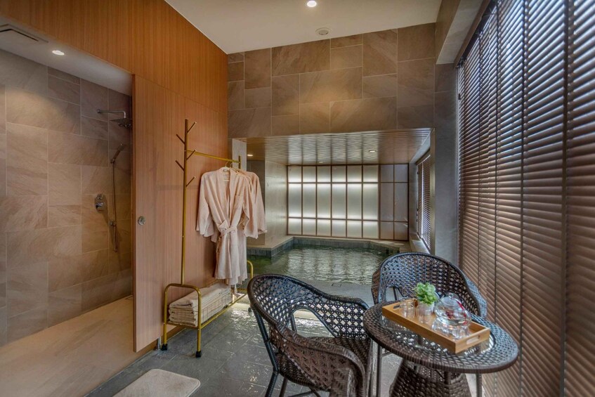 A modern bathroom with a glass-enclosed hot tub, a wooden vanity, and wicker chairs. 3