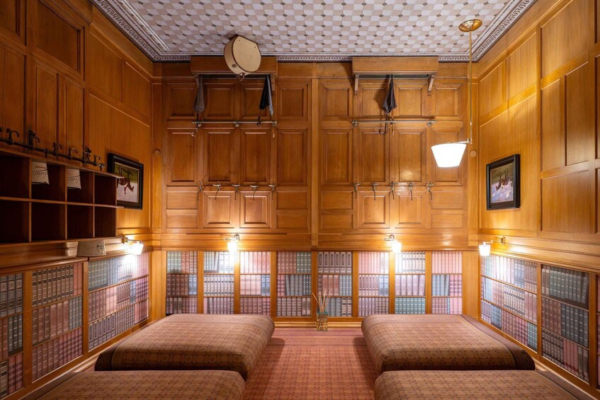 A library with wooden bookshelves, two beds, and a patterned carpet. 2