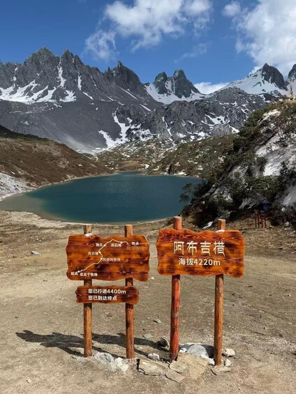 A mountainous landscape with a lake, wooden signs, and a clear sky. 1