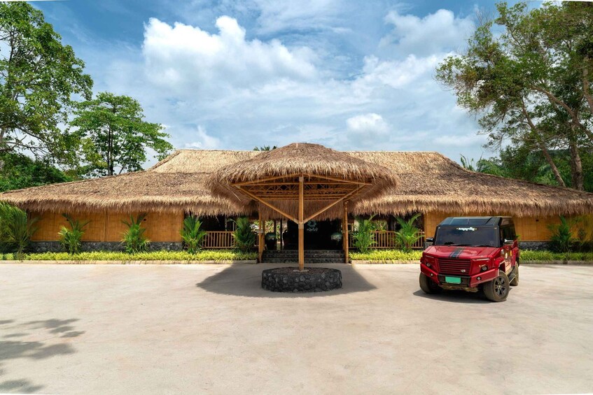 A thatched-roof structure with a vehicle parked in front. 5