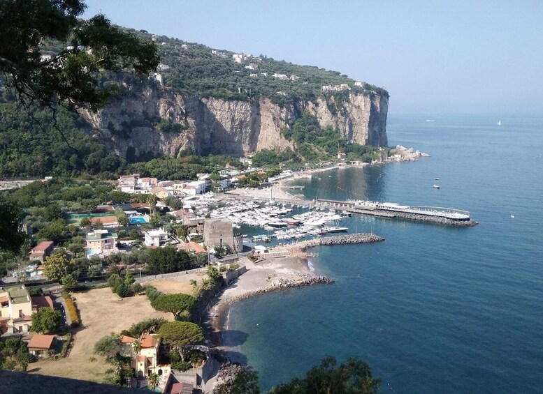 A coastal town with a marina, cliffs, and a clear sky. 1