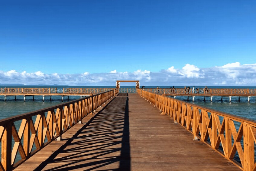 A wooden pier extending into calm waters, with a clear sky above. 3
