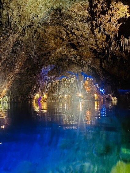 A cave with illuminated stalactites and a reflective water surface. 1