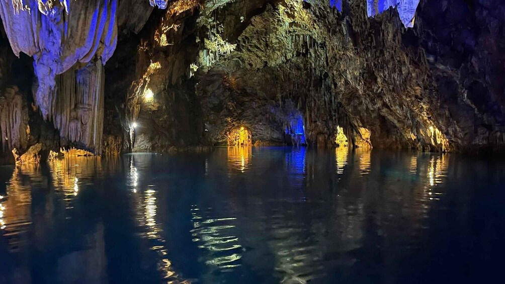A cave with illuminated stalactites and a calm pool of water. 3