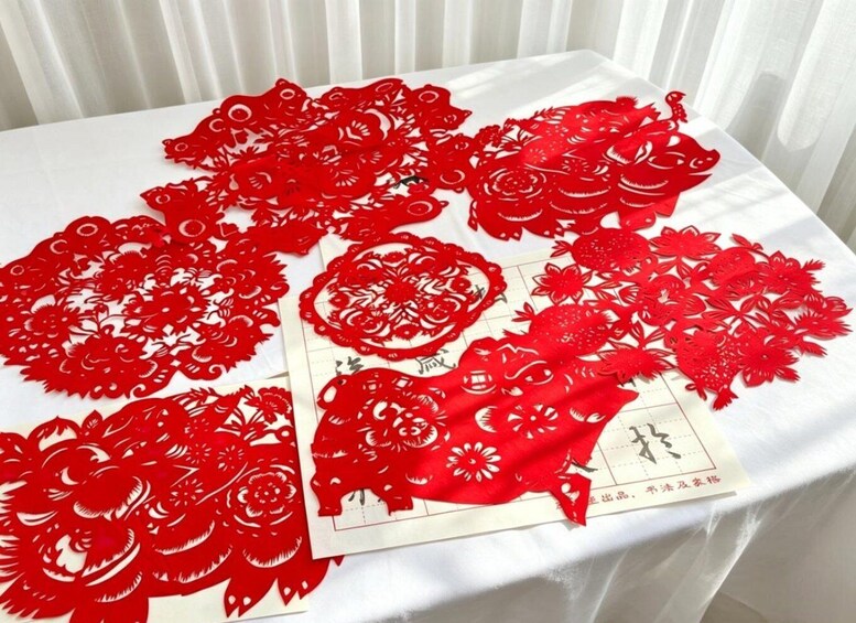 A table with red paper cuttings and a printed sheet. 1