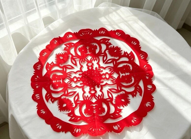 A red paper cut-out pattern on a white surface. 5