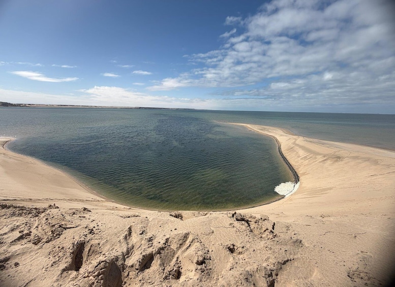 A coastal landscape with a large body of water, sandy beach, and distant shoreline. 1