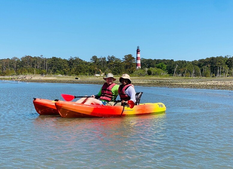 Two people kayaking on a calm river with a lighthouse in the background. 4