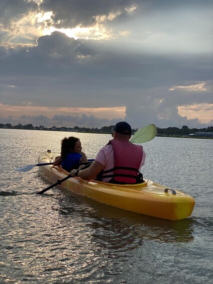 Two people kayaking on a calm body of water with a cloudy sky in the background. 5