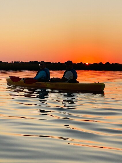 Two people kayaking on a calm body of water during sunset. 3