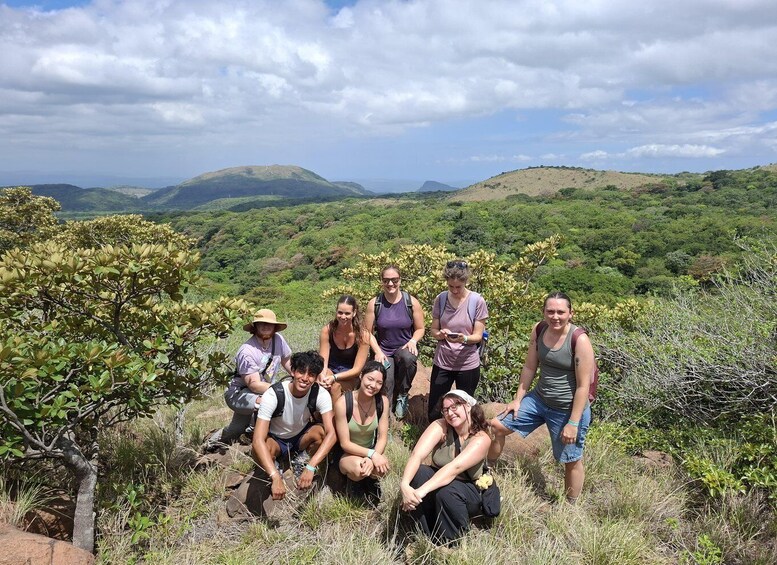 A group of people on a grassy hill with a mountainous landscape in the background. 3