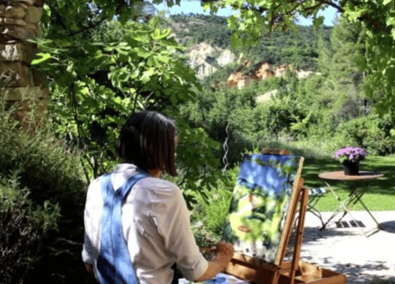 A person painting outdoors with a landscape in the background. 1