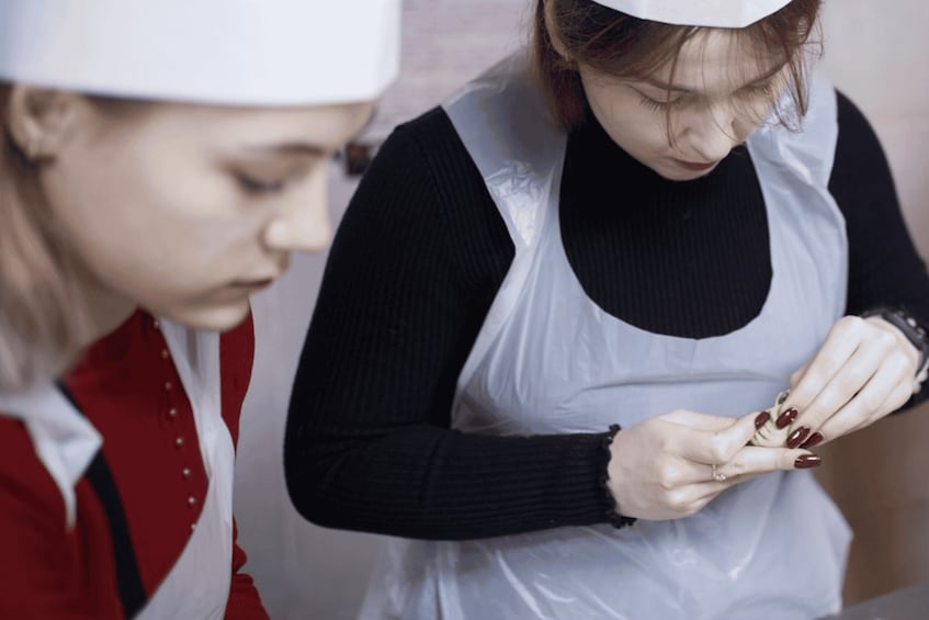 Two individuals in professional attire, one wearing a white chef's hat, engaged in food preparation. 3