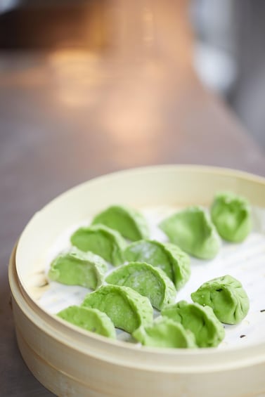 A bowl of green dumplings on a white plate. 4