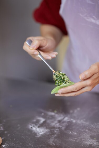 A person holding a spoon with a green substance, possibly food, on a dark surface. 2
