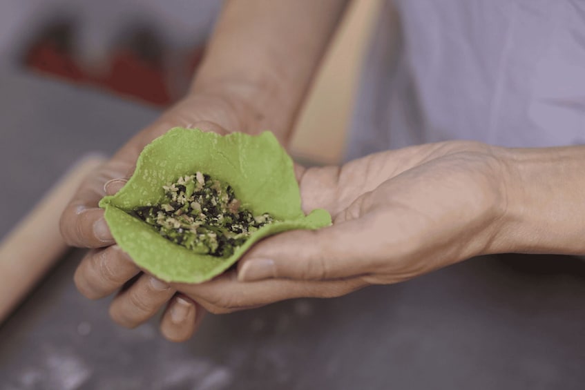 A person holding a green leaf-shaped object with seeds inside. 1