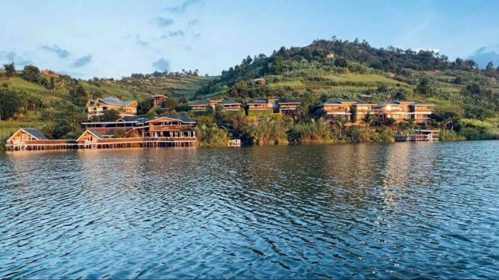 A lakeside resort with wooden chalets and a hilltop backdrop. 5