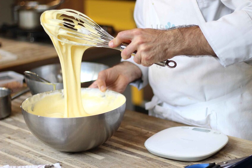 A person whisking a thick, yellow batter in a metal bowl. 5