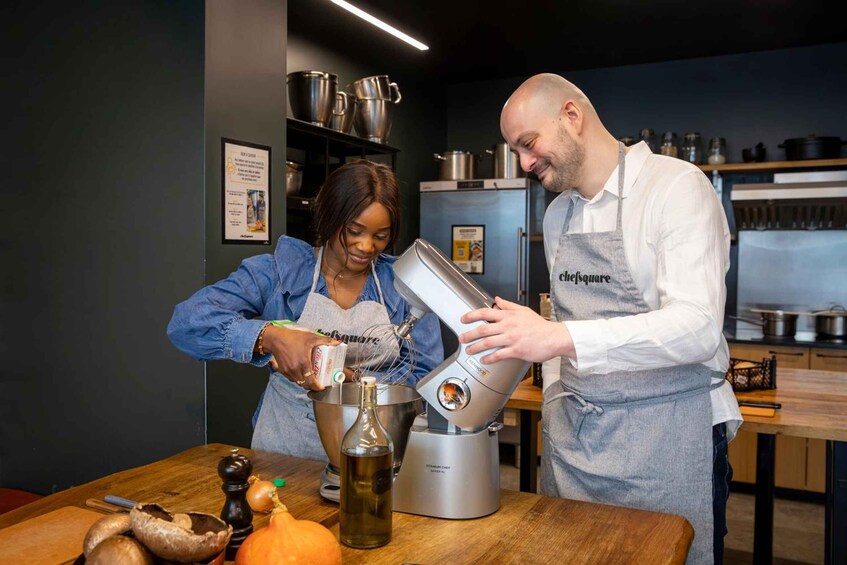Two people in a kitchen preparing food with a mixer. 4