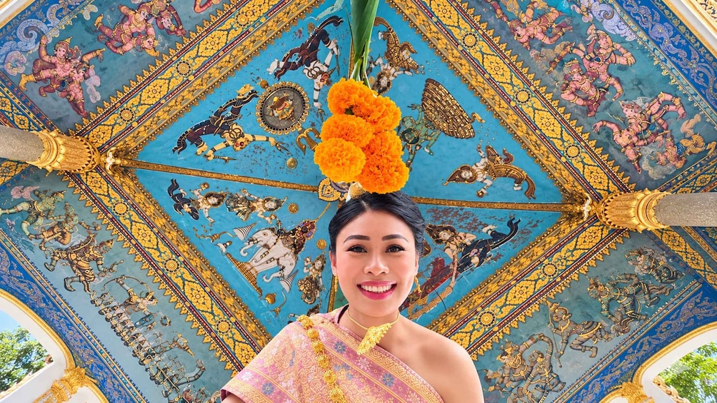A person in traditional attire with a blue and gold ceiling featuring intricate artwork. 3