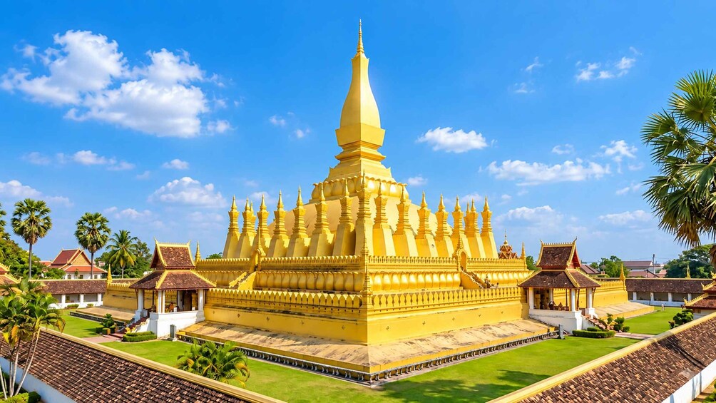 A golden temple with a tall spire, surrounded by smaller structures and palm trees. 5