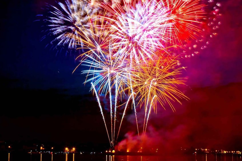 Fireworks exploding over a body of water at night. 2