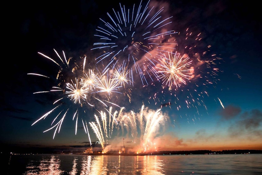 Fireworks over a body of water at dusk. 3