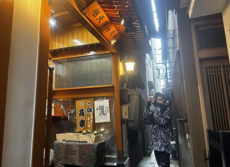 A narrow alleyway with wooden signage and traditional Japanese decorations. 2