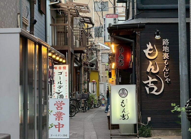 A narrow urban street with traditional Japanese signage, bicycles, and a mix of commercial and residential buildings. 3