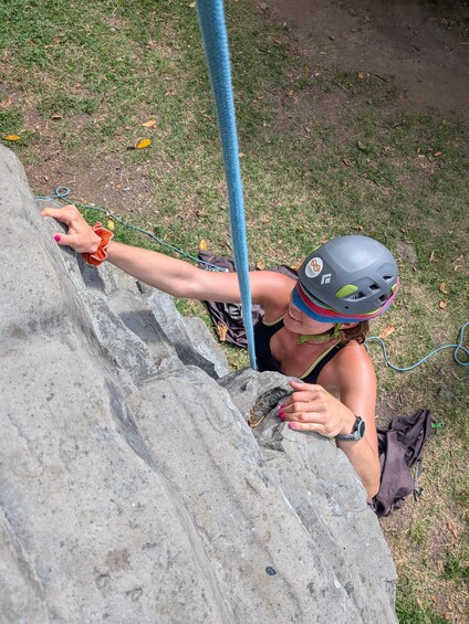 A person climbing a rock face with a helmet and climbing gear. 2