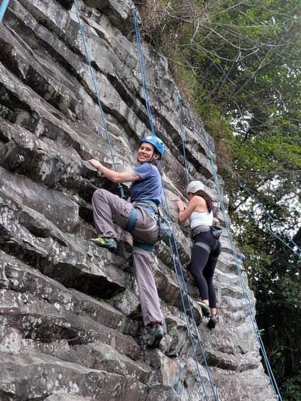 Two people rock climbing a rocky cliff with ropes. 1