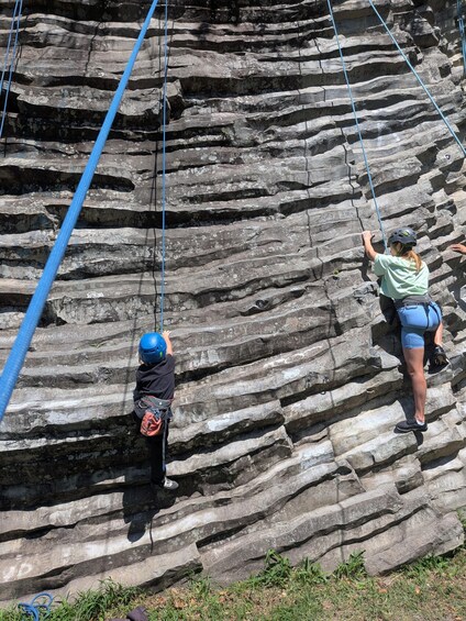 Two people rock climbing on a layered rock face. 3