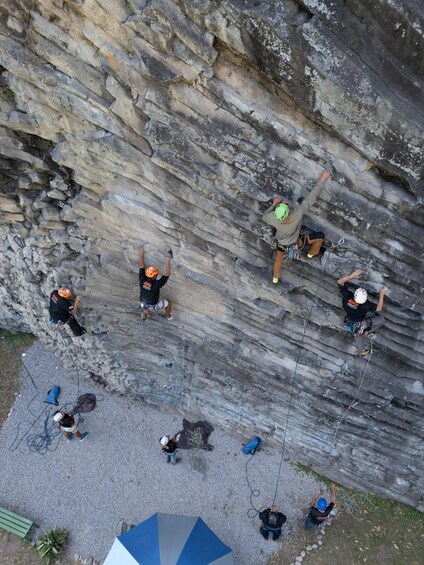 A group of people engaged in rock climbing on a large rock face. 4