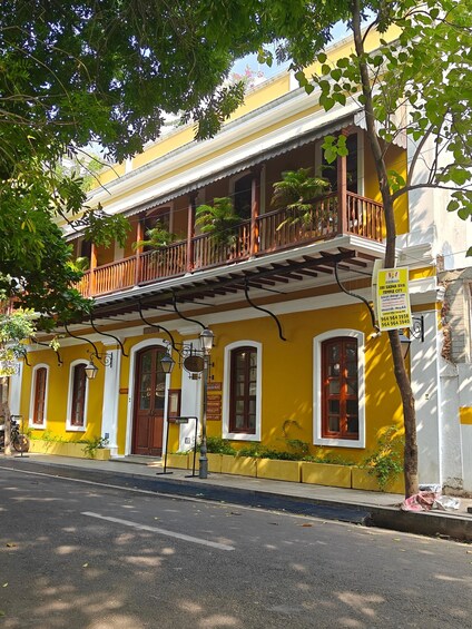 A yellow building with a balcony, a signboard, and a street in front. 2