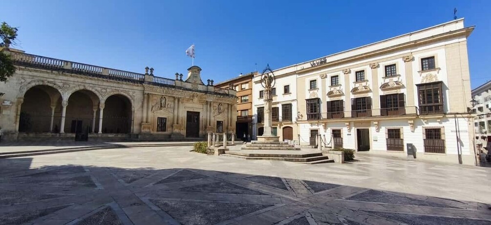 A historic plaza with a fountain, arches, and classical buildings. 5