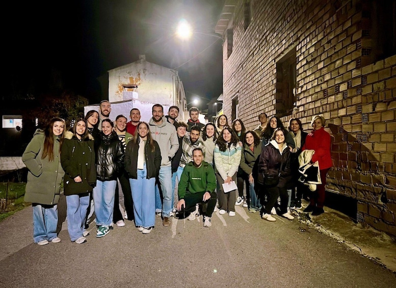 A group of people standing in front of a brick building at night. 3