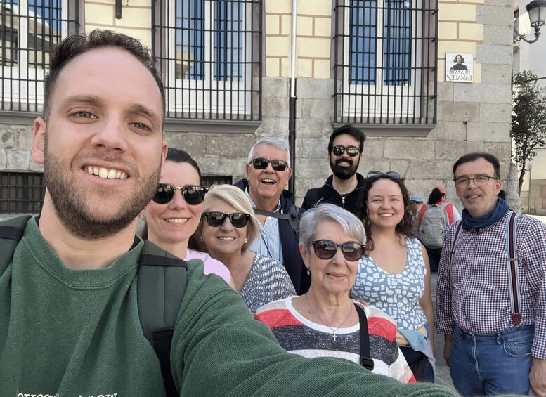 A group of people taking a selfie in front of a building with barred windows and a sign that reads 'PRESIDENT'. 2